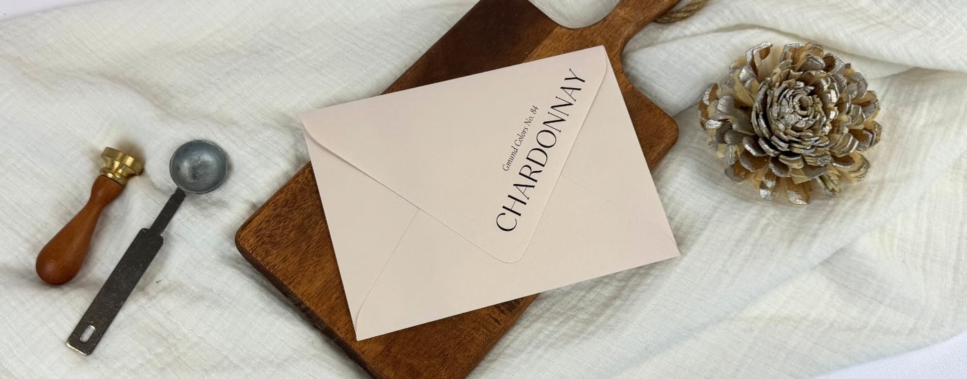 black ink printed Chardonnay beige envelopes at LCI on a white linen blanket and brown wooden tray