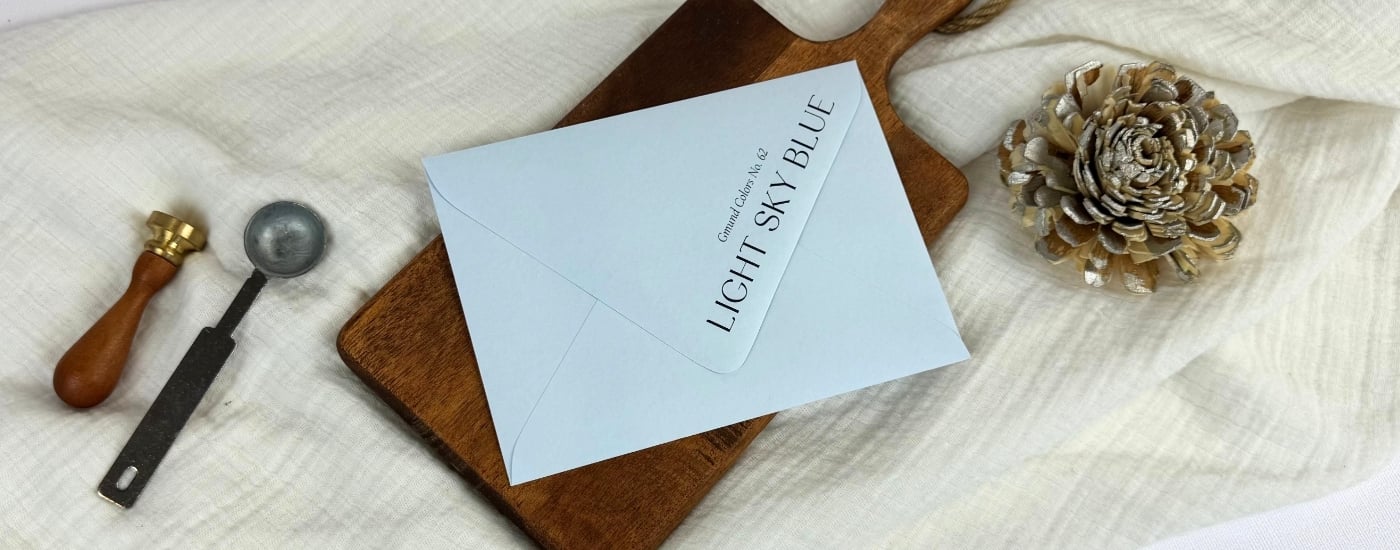 black ink printed Light Sky Blue envelopes at LCI on a white linen blanket and brown wooden tray