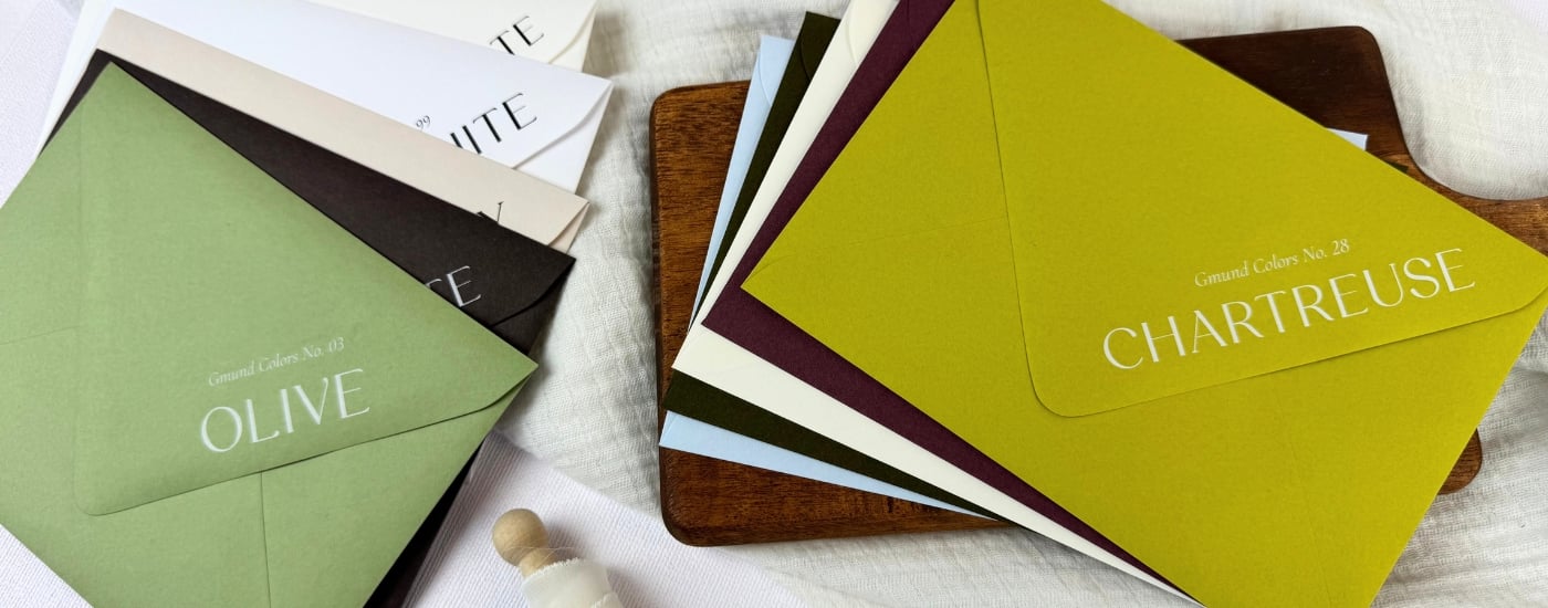 top 10 Gmund Colors Matt colored envelopes at LCI on a white linen blanket and brown wooden tray